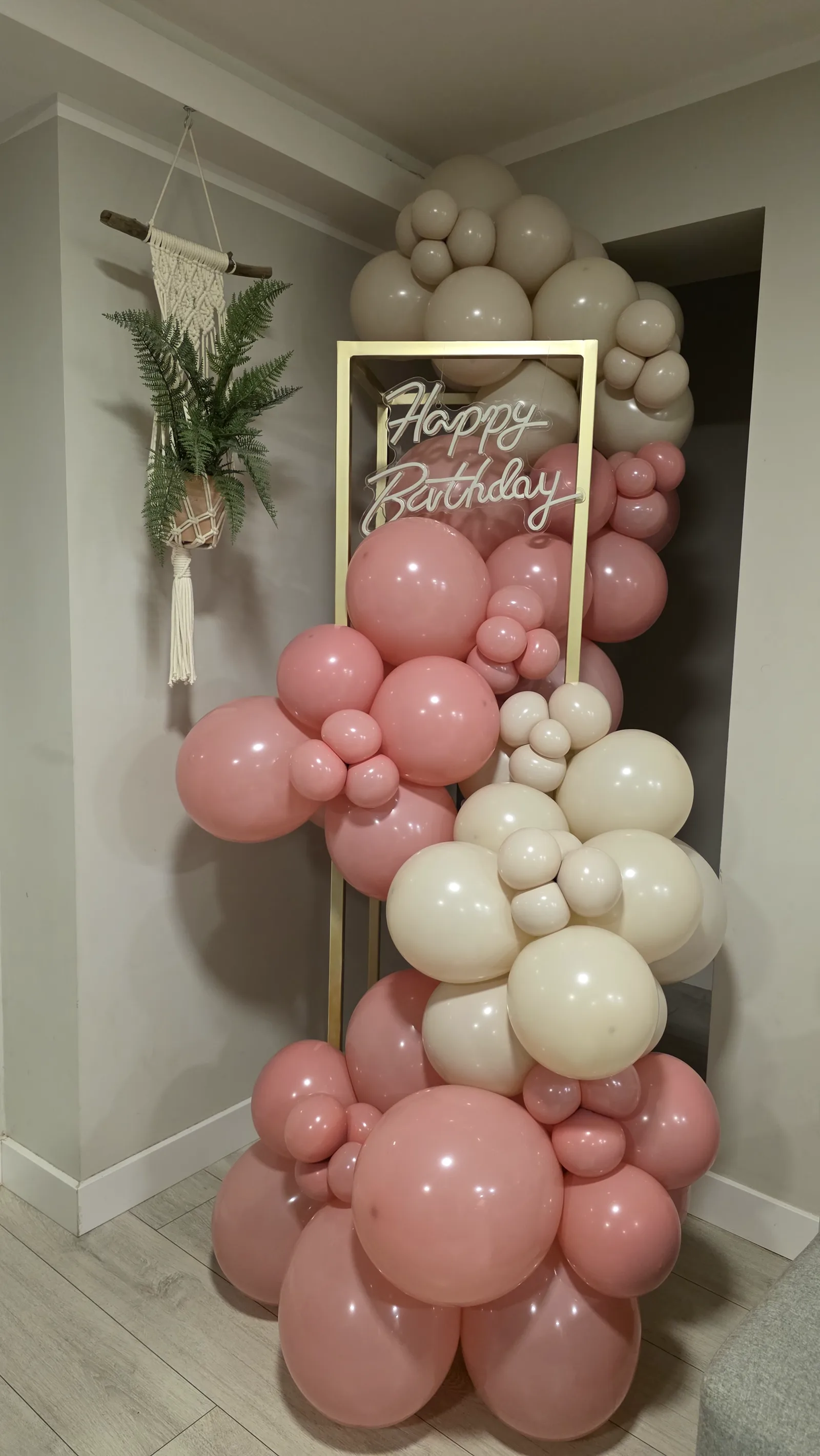 Złoty stelaż z neonem Happy Birthday i girlandą z różowych i kremowych balonów