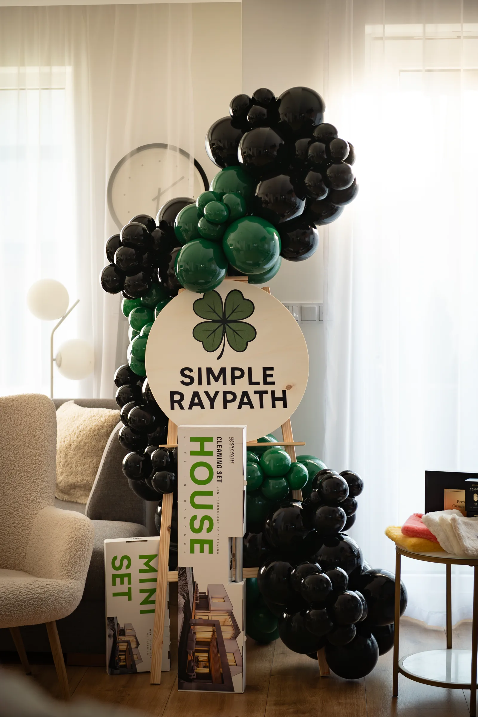 Sztaluga z okrągłą tablicą z logo Simple Raypath i girlandą z czarnych i zielonych balonów na evencie firmowym